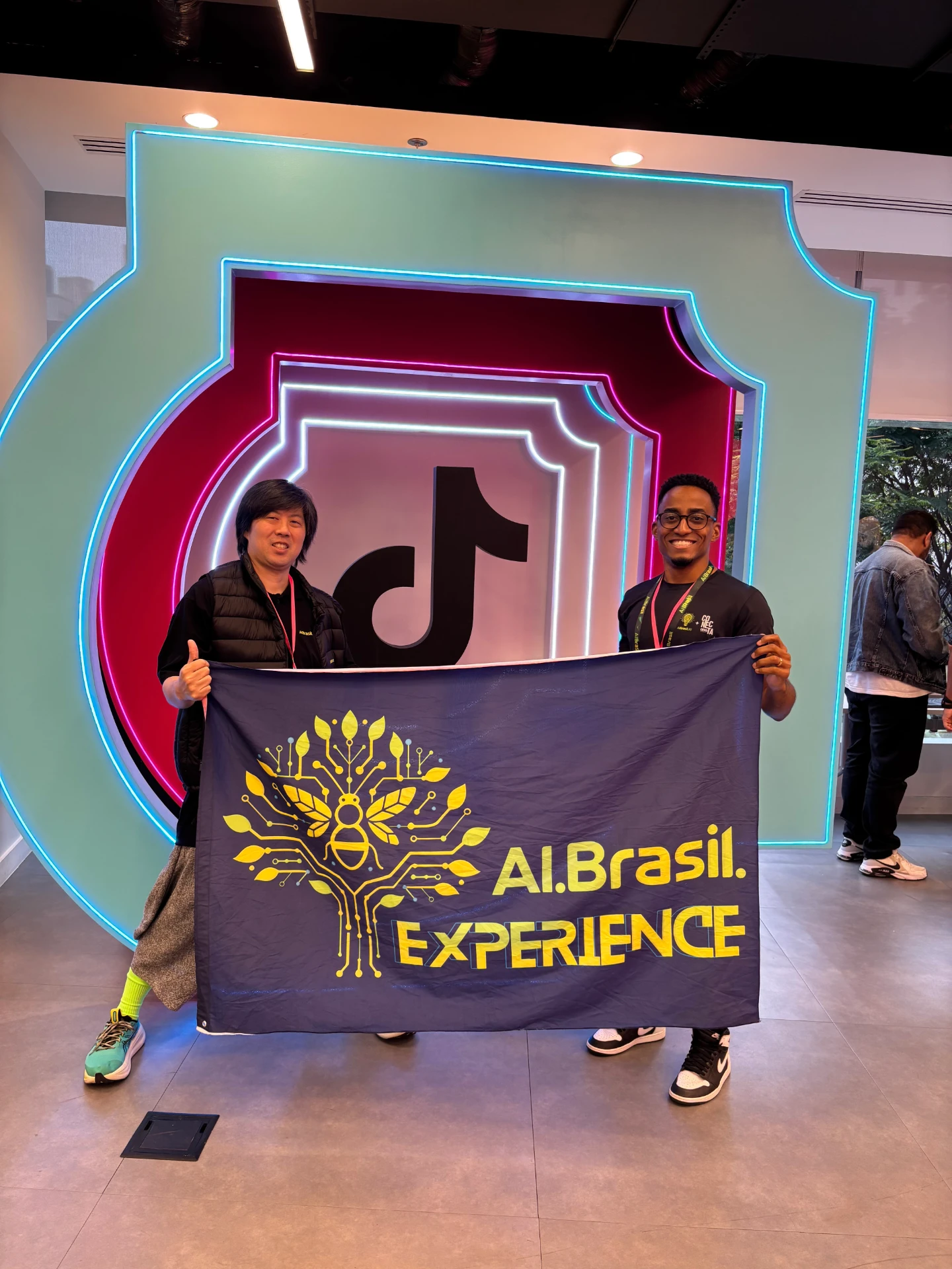 Gabriel Virissimo com a bandeira do AI.Brasil Experience no escritório do TikTok