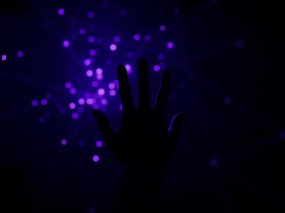 Mão humana alcançando pontos de luz violeta na escuridão